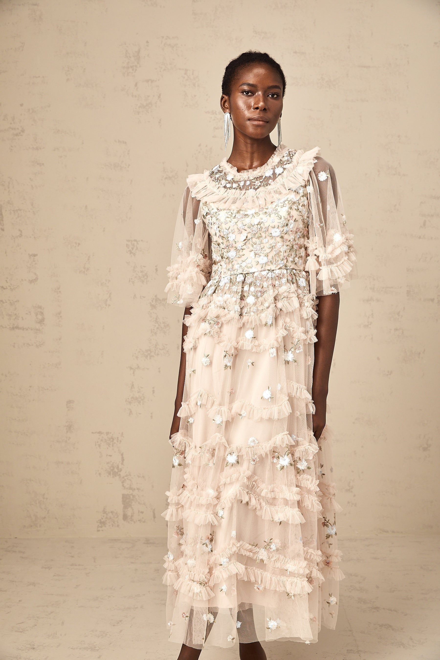 A white midi dress with tiered ruffles and floral embroidery details featuring a fitted bodice and flowing skirt