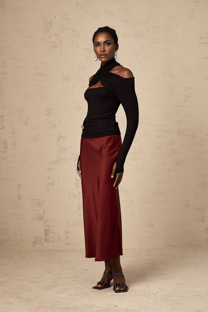 Woman wearing a black formfitting top with ruched detailing and long sleeves made from stretchy jersey fabric