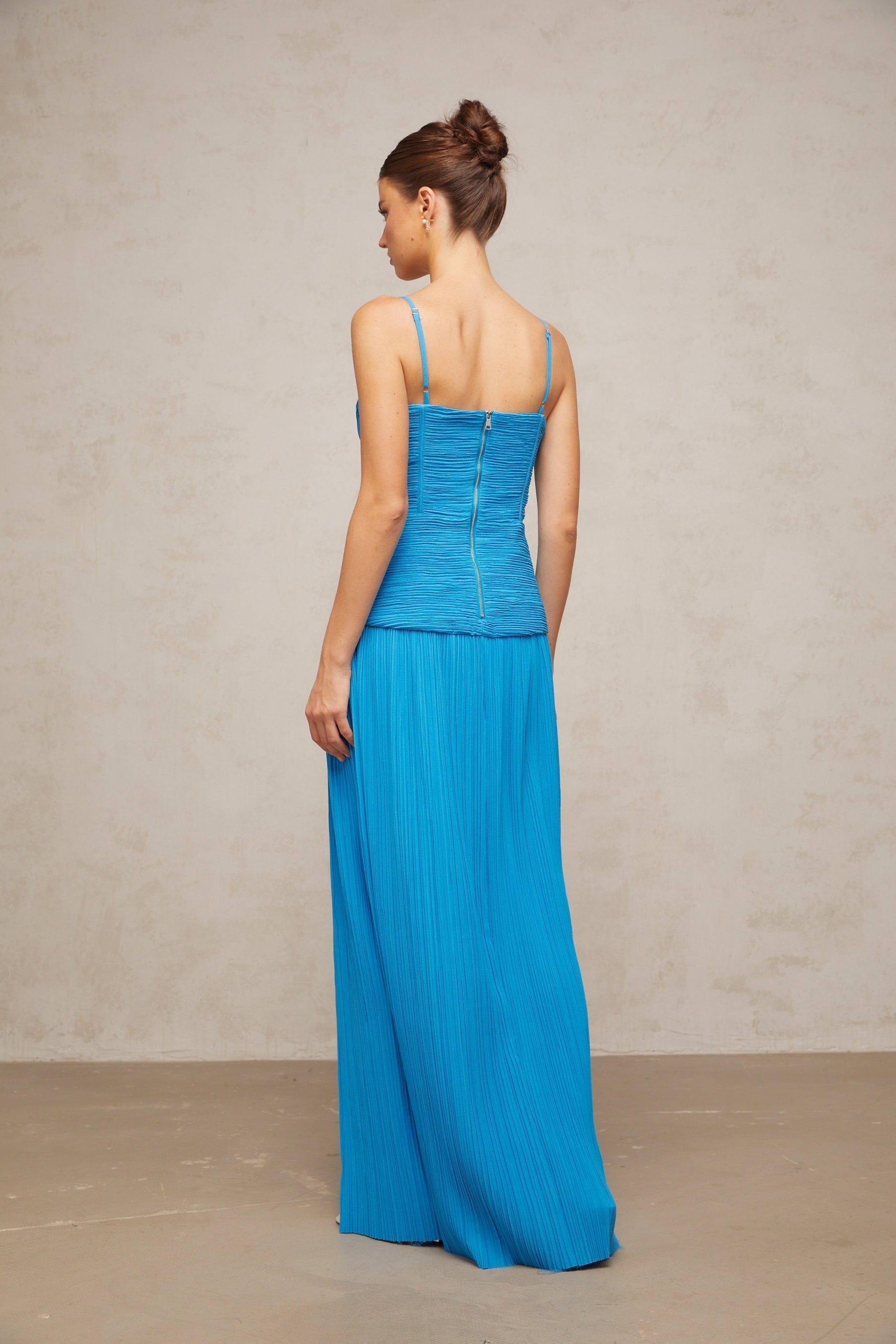 A blue pleated maxi dress with side slits and a flowing silhouette