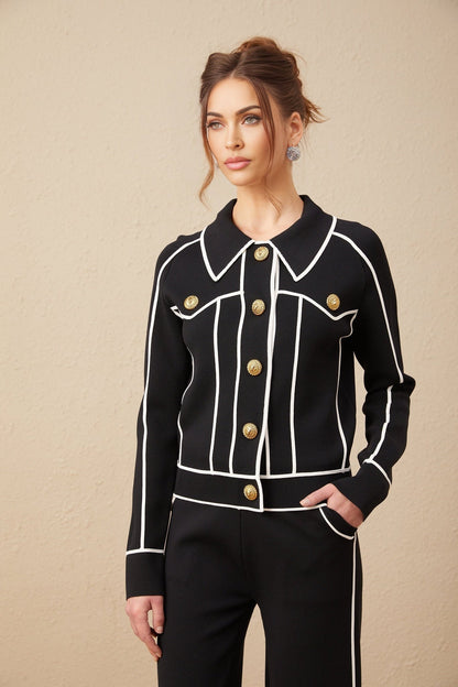 Woman wearing black jacket and trousers set with white piping detail
