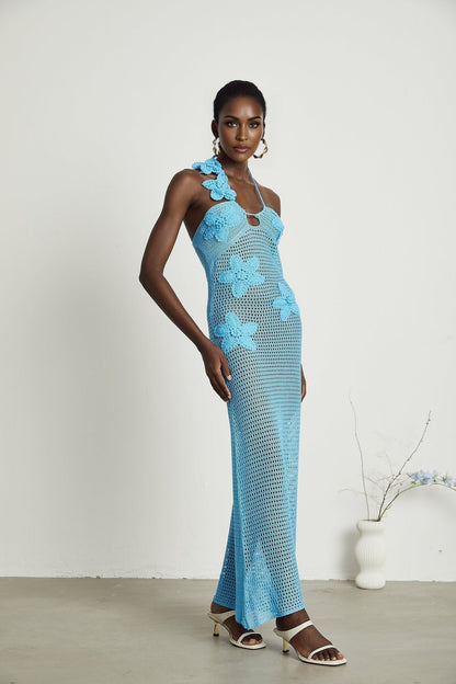 A long white crochet maxi dress with colorful faux flower embellishments scattered throughout the design