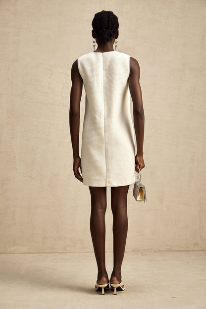 A woman wearing a short tweed dress with embroidery details and cutout sections