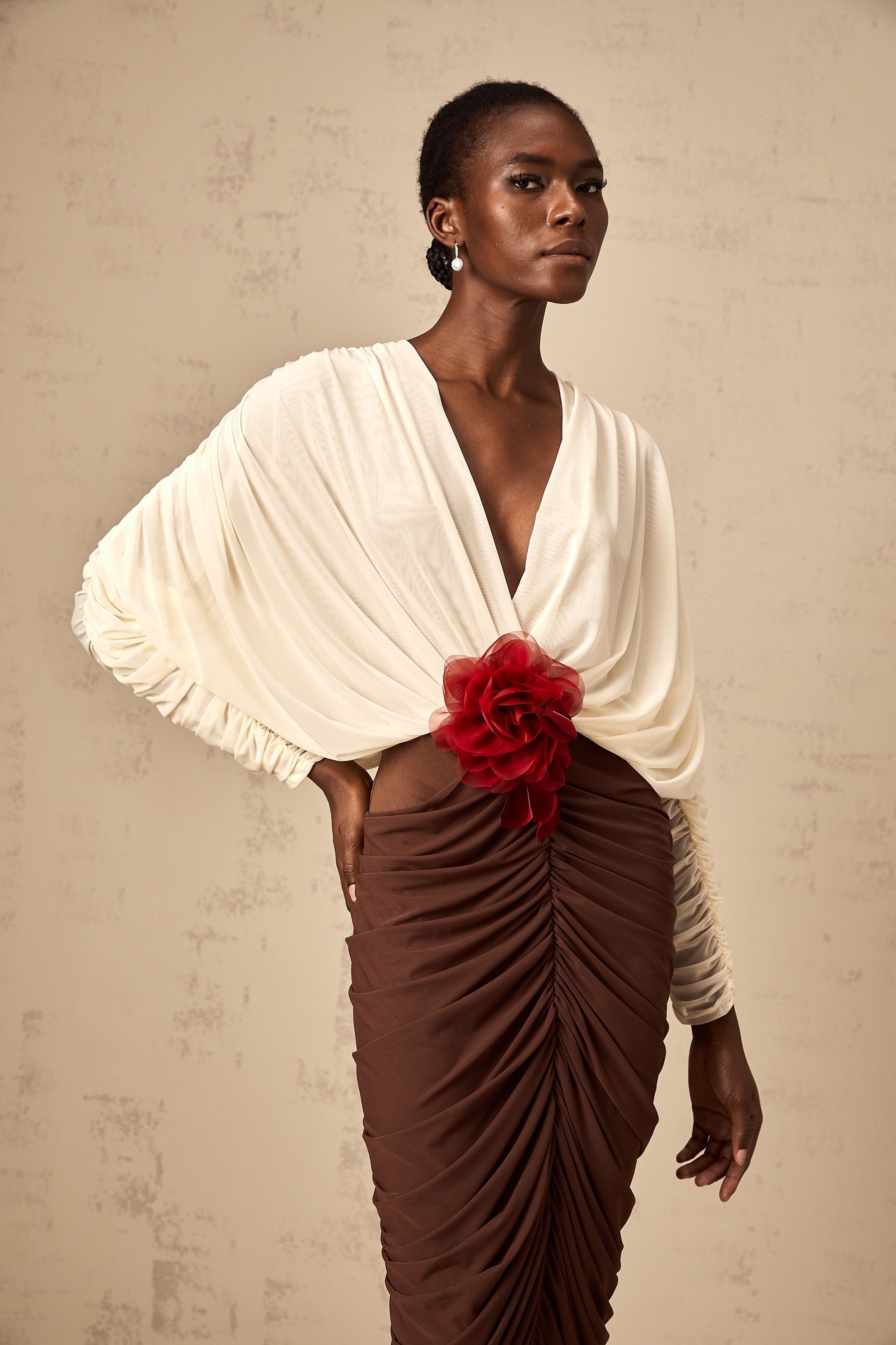 A midi dress with ruched detailing featuring colorblocked sections and a decorative flower brooch The dress is named Leontine and appears to be a stylish womens garment