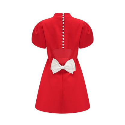 Woman wearing red mini dress with petal sleeves cut out details and bow accent
