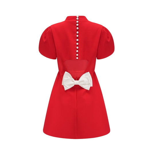 Woman wearing red mini dress with petal sleeves cut out details and bow accent