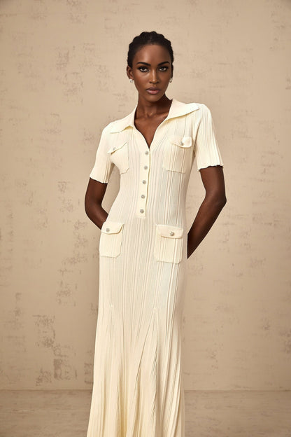 A woman wearing a formfitting ribbed knit midi dress in a neutral color standing in a relaxed pose