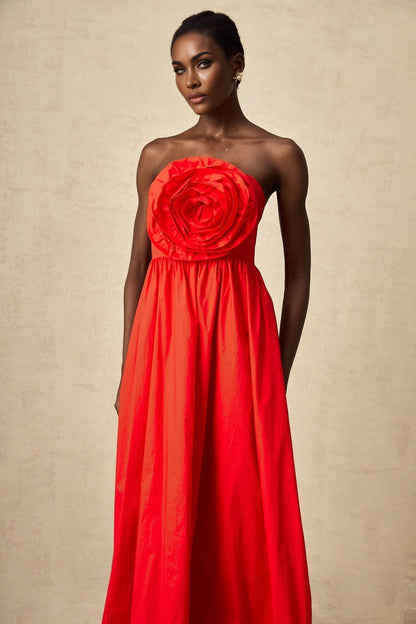 Woman wearing a long red maxi dress with layered 3d petal ruffles cascading down the skirt