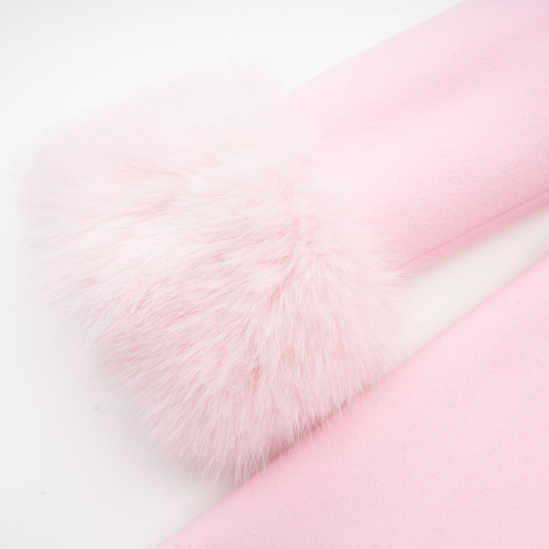 A pink fluffy overcoat with a plush faux fur texture hanging on a coat hanger