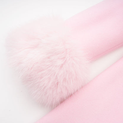 A pink fluffy overcoat with a plush faux fur texture hanging on a coat hanger