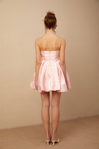 Woman wearing pink off shoulder mini dress with puff sleeves made of satin material