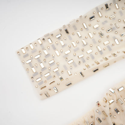 A short sleeveless mini dress with crystal embellishments and draped fabric detail