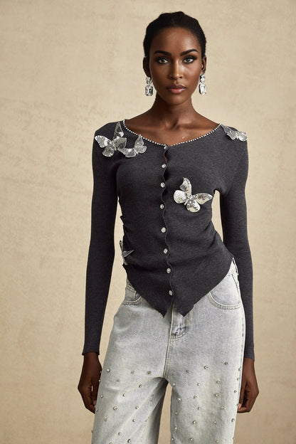 A grey cardigan with sequined butterfly designs adorning the fabric