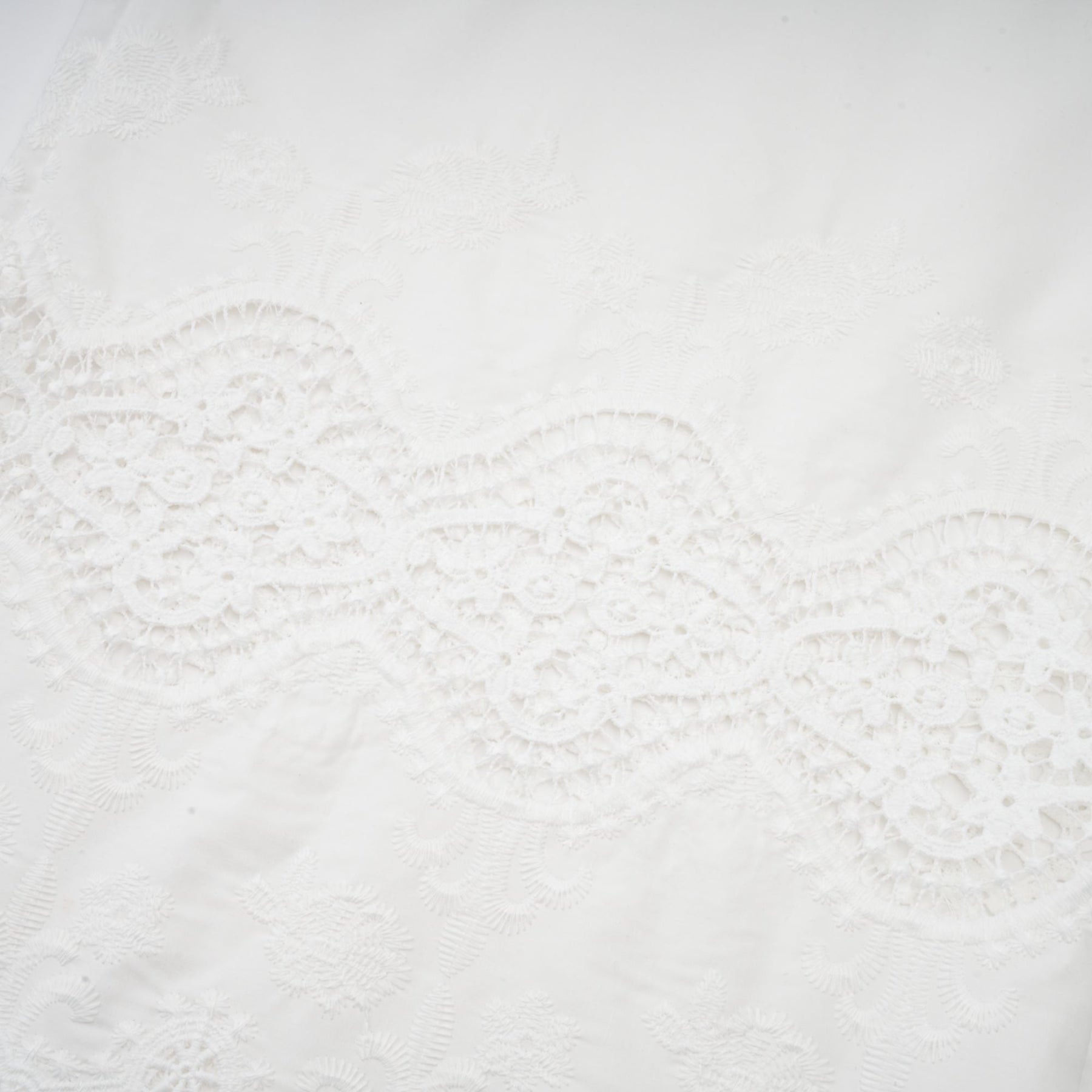 Woman wearing a matching set of white lace trim cropped top and trousers with cutout details