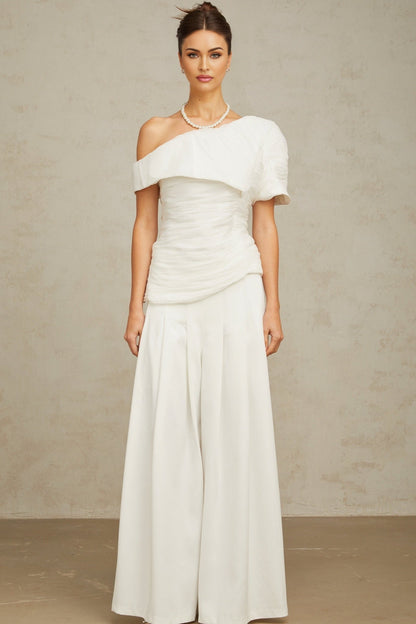 A white matching set featuring a creased top and trousers worn by a model standing against a plain background