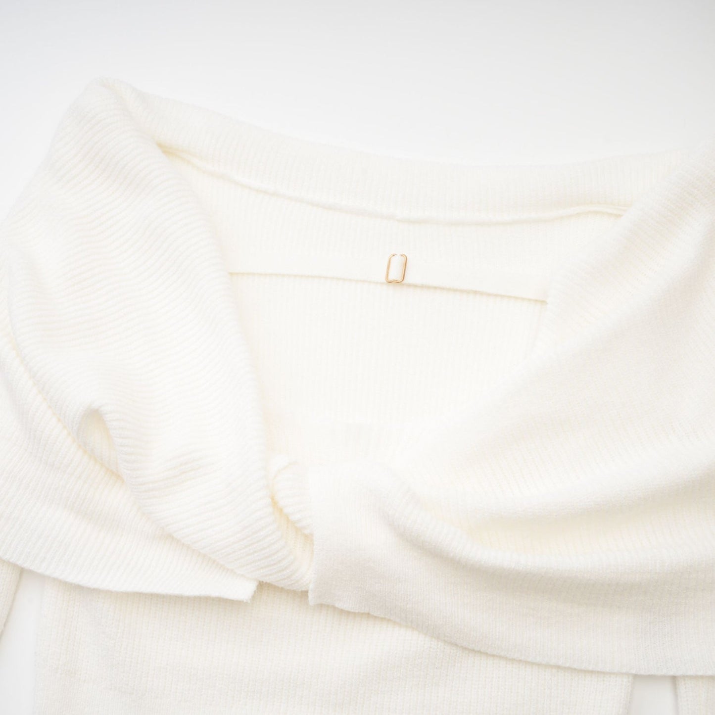 Woman wearing a white knitted strapless long sleeve top with textured pattern