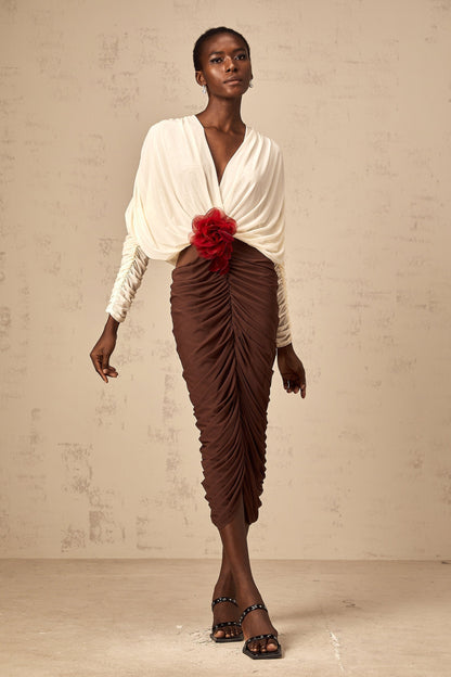 A midi dress with color blocking and ruching featuring a flower brooch The dress is named Leontine and has a mid length design