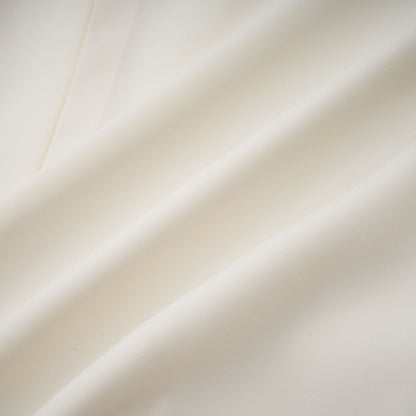 Woman wearing white pleated jacket and dress set with embellishments Blanche design