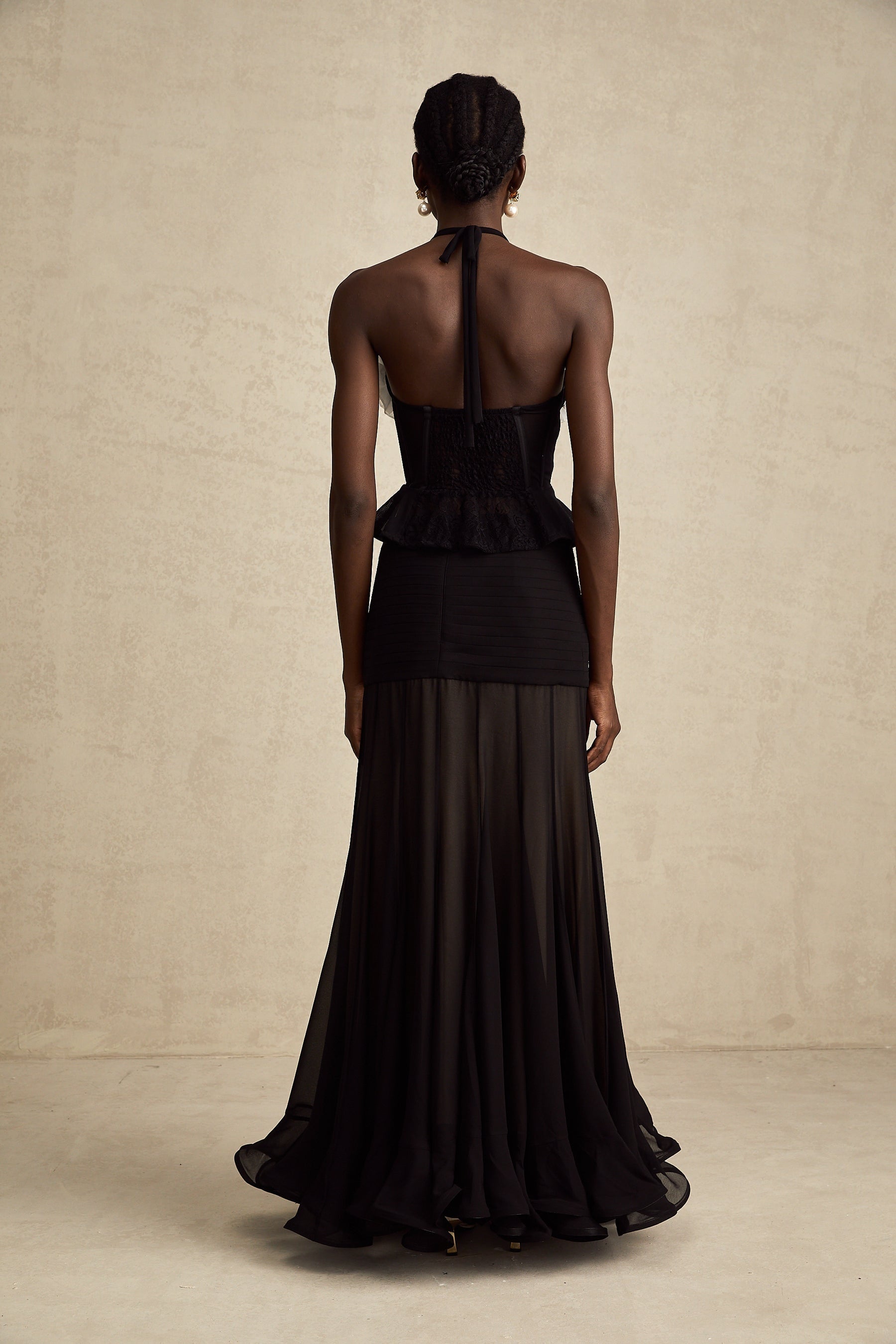 A black corset top with floral lace detailing and faux flower embellishments on a plain background