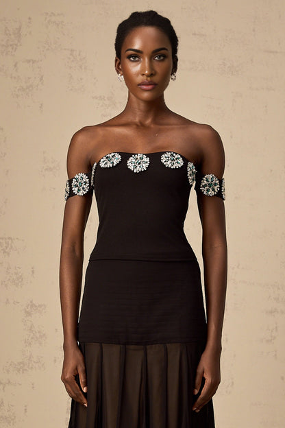 A woman wearing a black offshoulder top with embellishments named Carina
