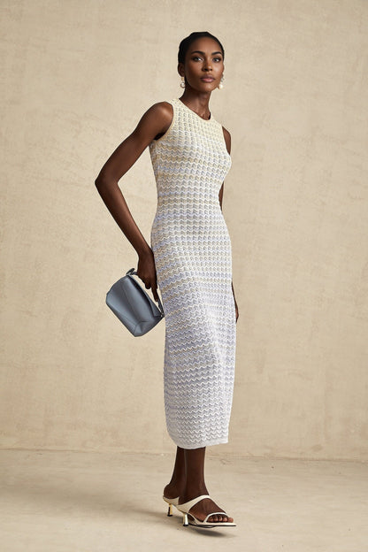 Woman wearing a long ribbed knit dress with contrasting color details and midi length