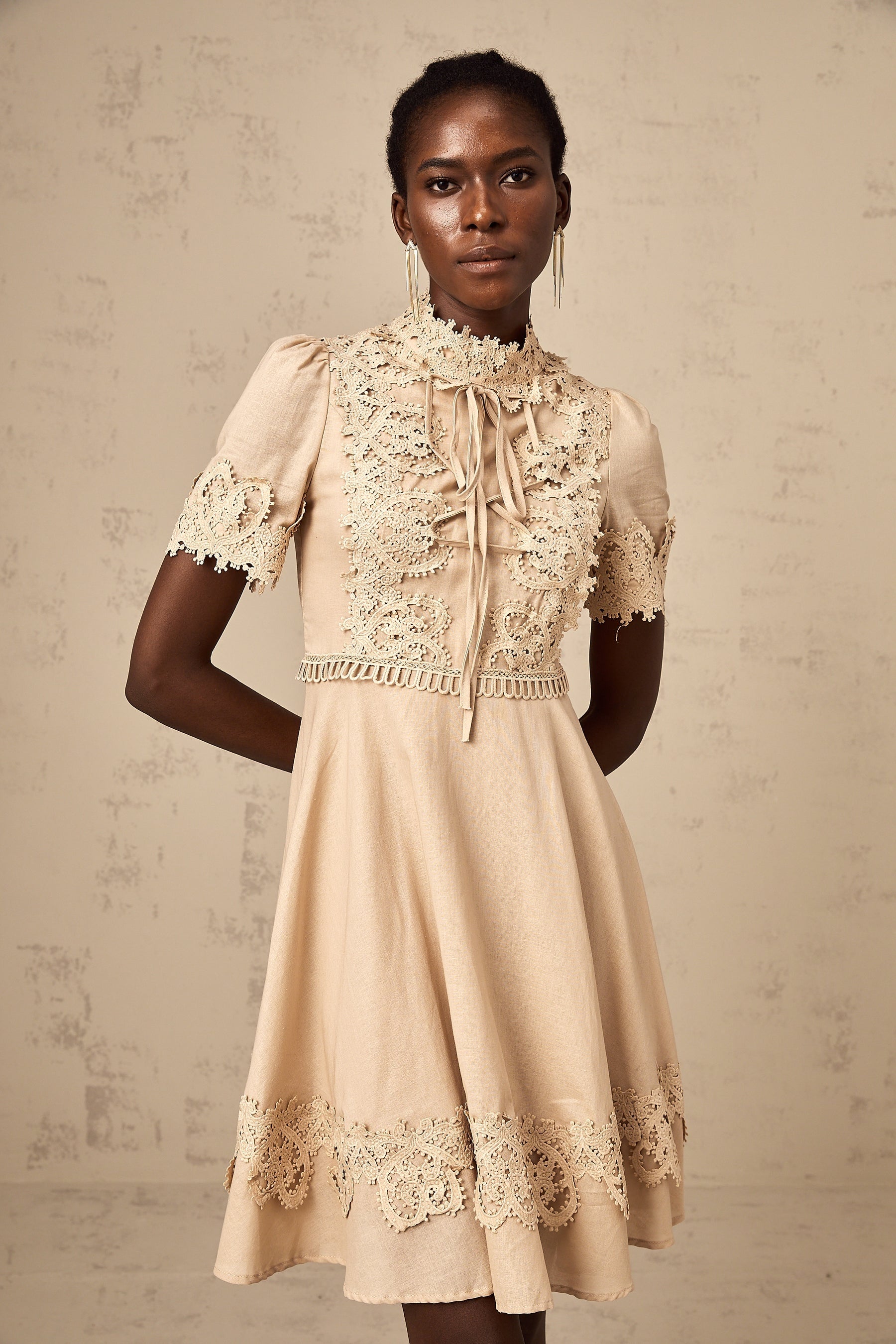 A woman wearing a short flared mini dress with corded lace detailing and a feminine silhouette