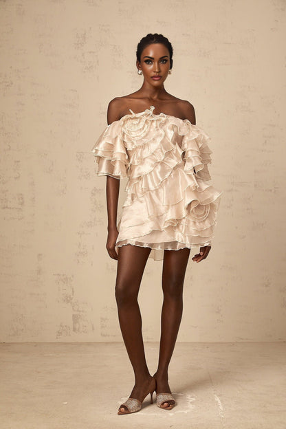 A neutral colored mini dress with an asymmetric design featuring a cerise flounce detail