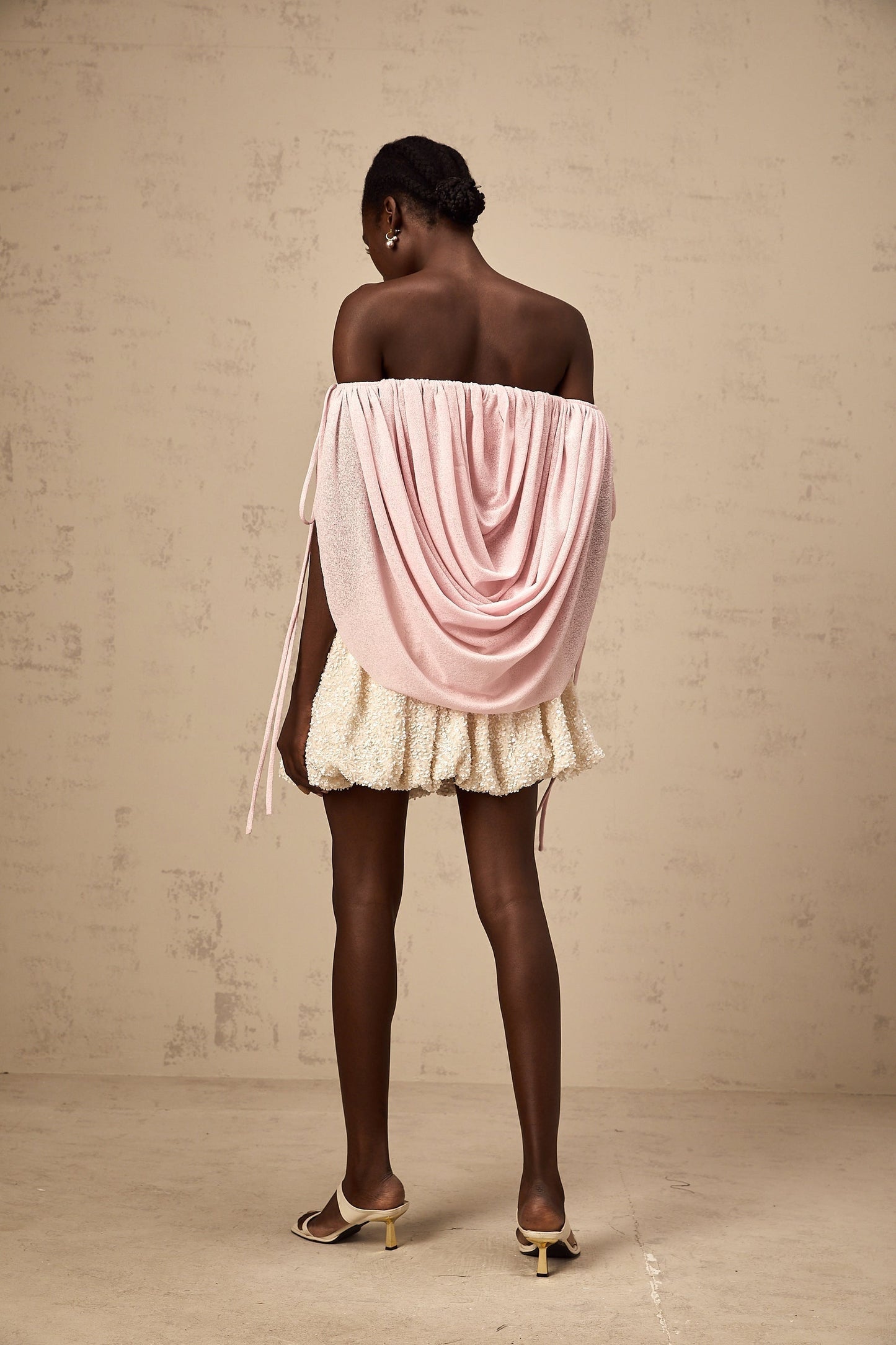 A woman wearing a pink offshoulder top with ruched detailing