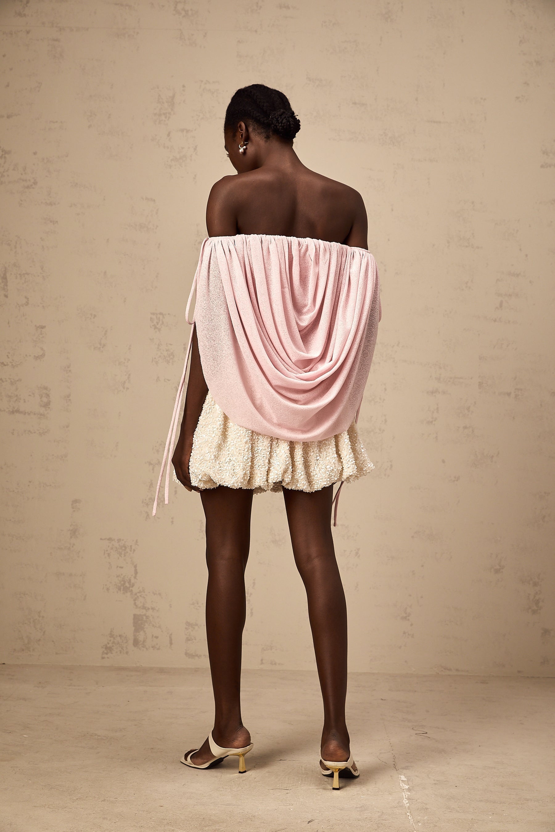 A woman wearing a pink offshoulder top with ruched detailing