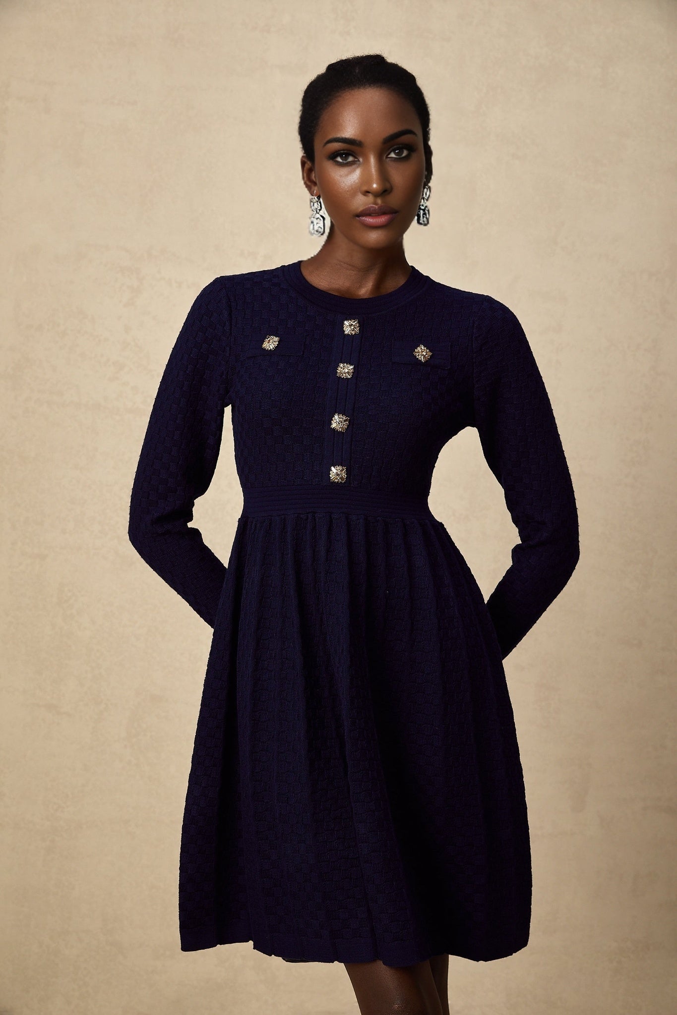 A navy blue mini dress with a basketweave texture worn by a model standing against a plain background