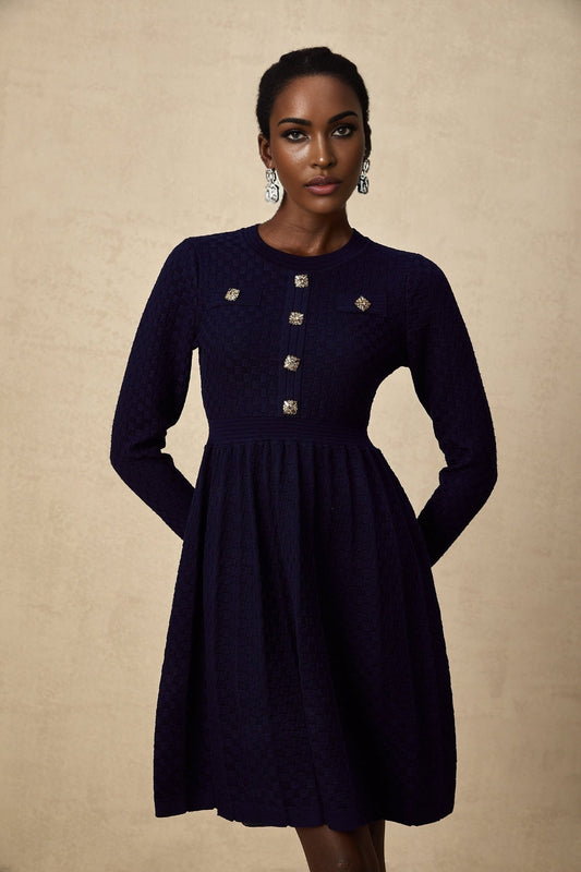 A navy blue mini dress with a basketweave texture worn by a model standing against a plain background