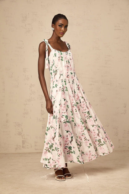 A long pink maxi dress with a floral print pattern and tied straps