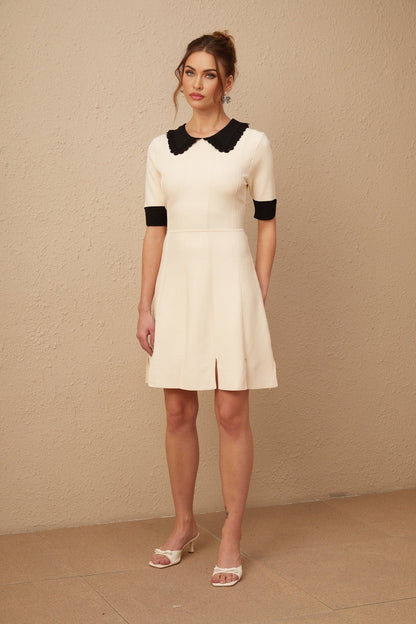 Woman wearing a white knitted mini dress with split hem detail and short sleeves