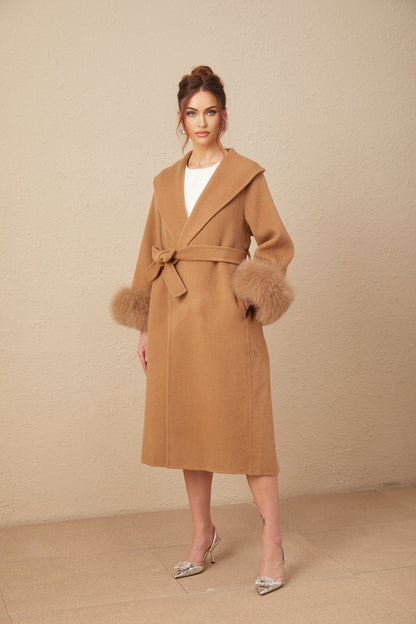 A woman wearing a long brown woolen wrap overcoat with a felted texture standing against a plain background