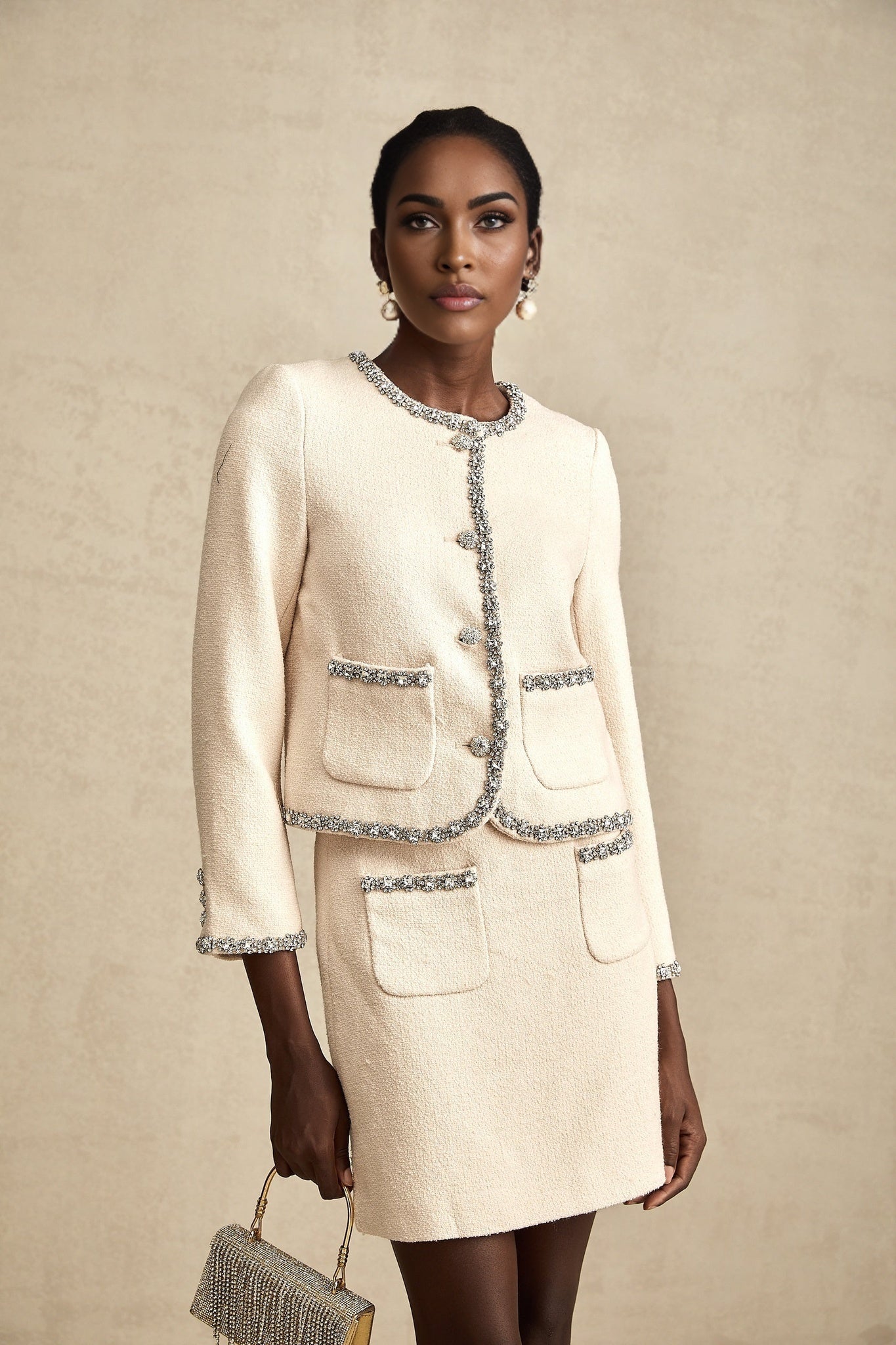 A beige tweed cardigan and matching skirt set with crystal embellishments featuring a classic Elisabeth style design