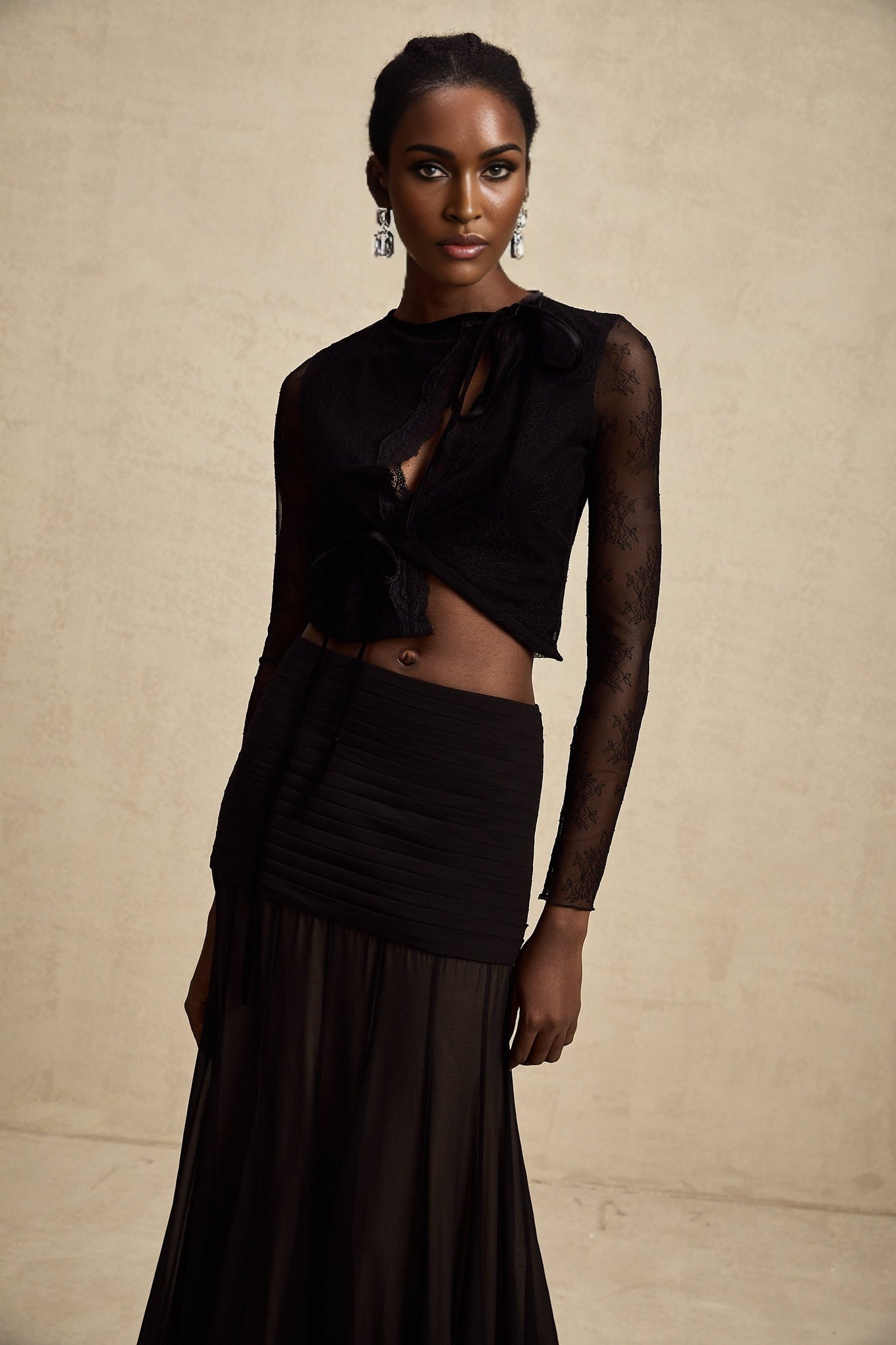 A black cropped top with sheer lace trim and see through details worn by a model