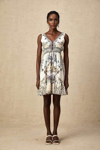 A woman wearing a short floral print dress with a vneck neckline The dress features a vibrant pattern and falls above the knee