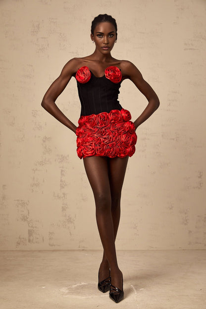 A woman wearing a red matching set consisting of a top and skirt adorned with rose appliques