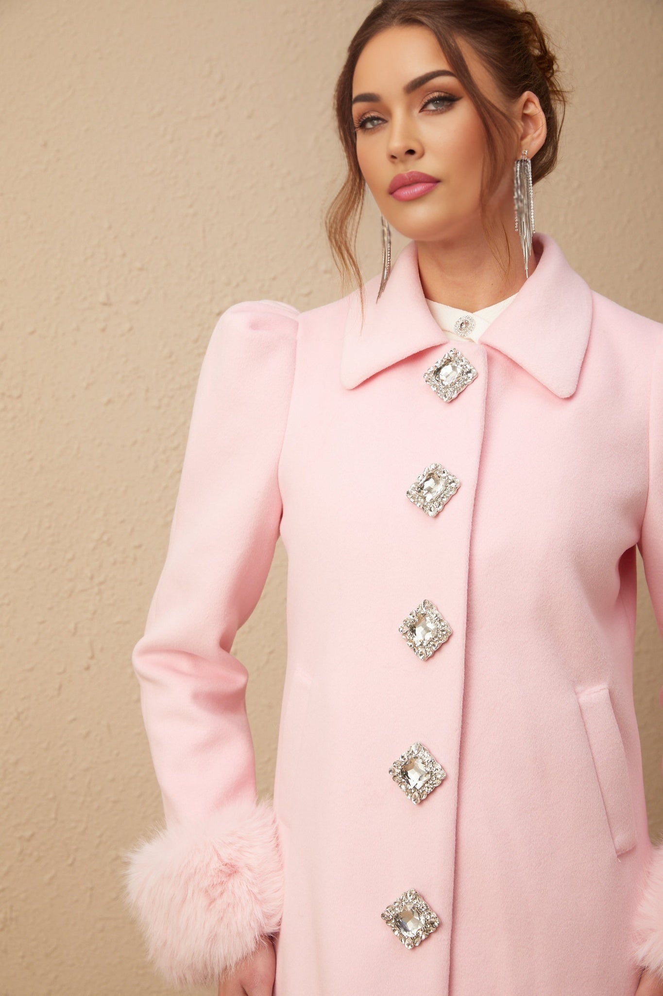 A pink overcoat made of faux fur named Louisette shown on a mannequin or hanger against a plain background