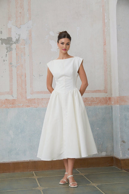 A woman wearing a white midi dress with cap sleeves and an open back design