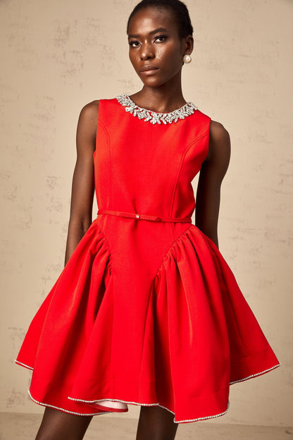 Woman wearing a short red dress with pleated skirt and embellished details