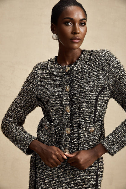 A woman wearing a matching set consisting of a jacket and skirt in contrasting colors with shimmery lurex fabric details