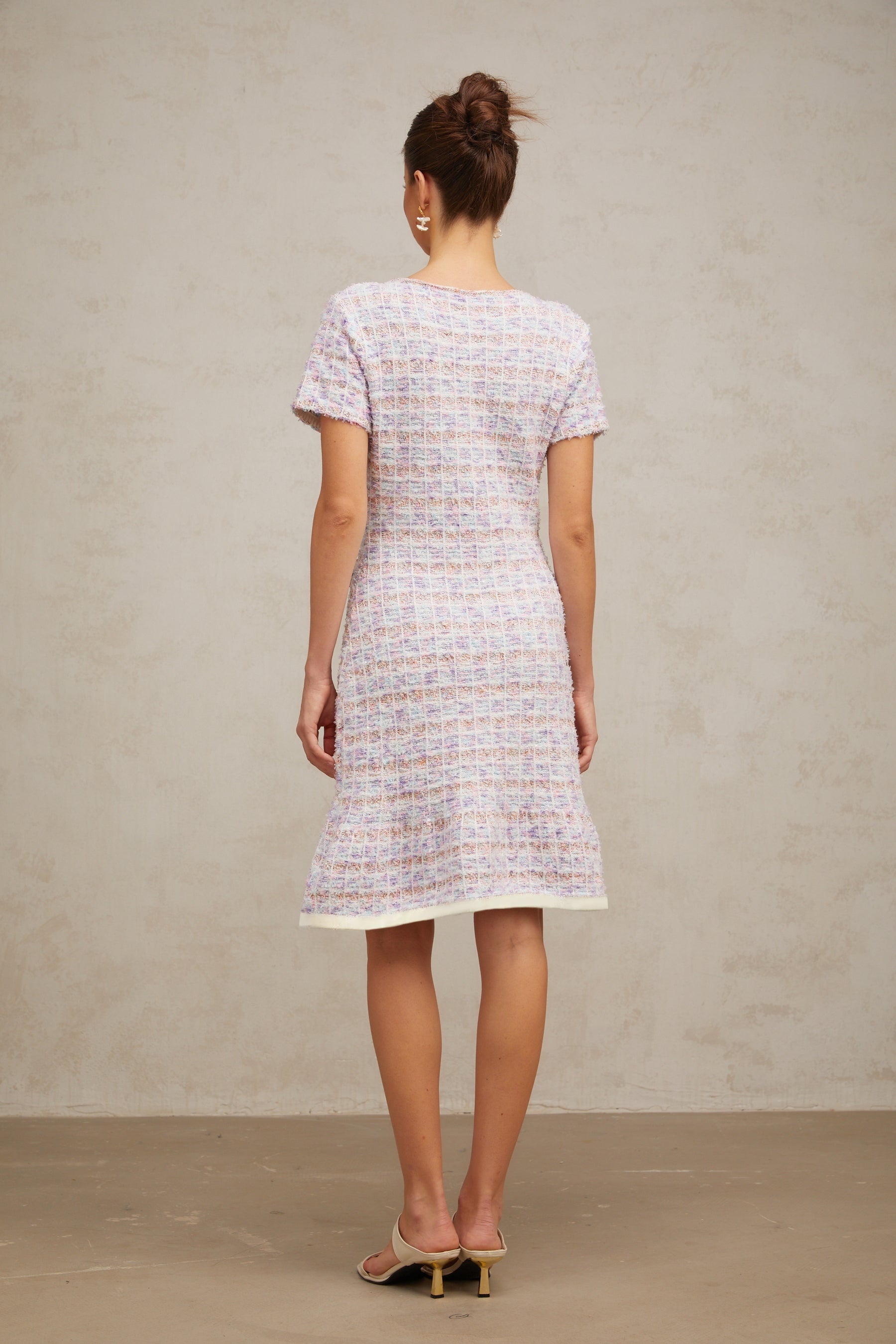 Woman wearing a purple checked knit midi dress with long sleeves and a fitted silhouette standing against a plain background