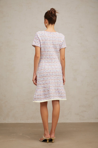Woman wearing a purple checked knit midi dress with long sleeves and a fitted silhouette standing against a plain background