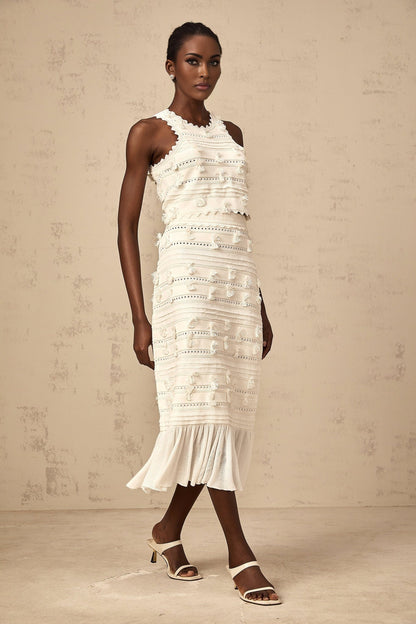 A white knit twopiece outfit consisting of a top and skirt with pointelle trim details The top is sleeveless and the skirt is kneelength Both pieces feature a textured knit pattern and delicate eyelet designs along the edges