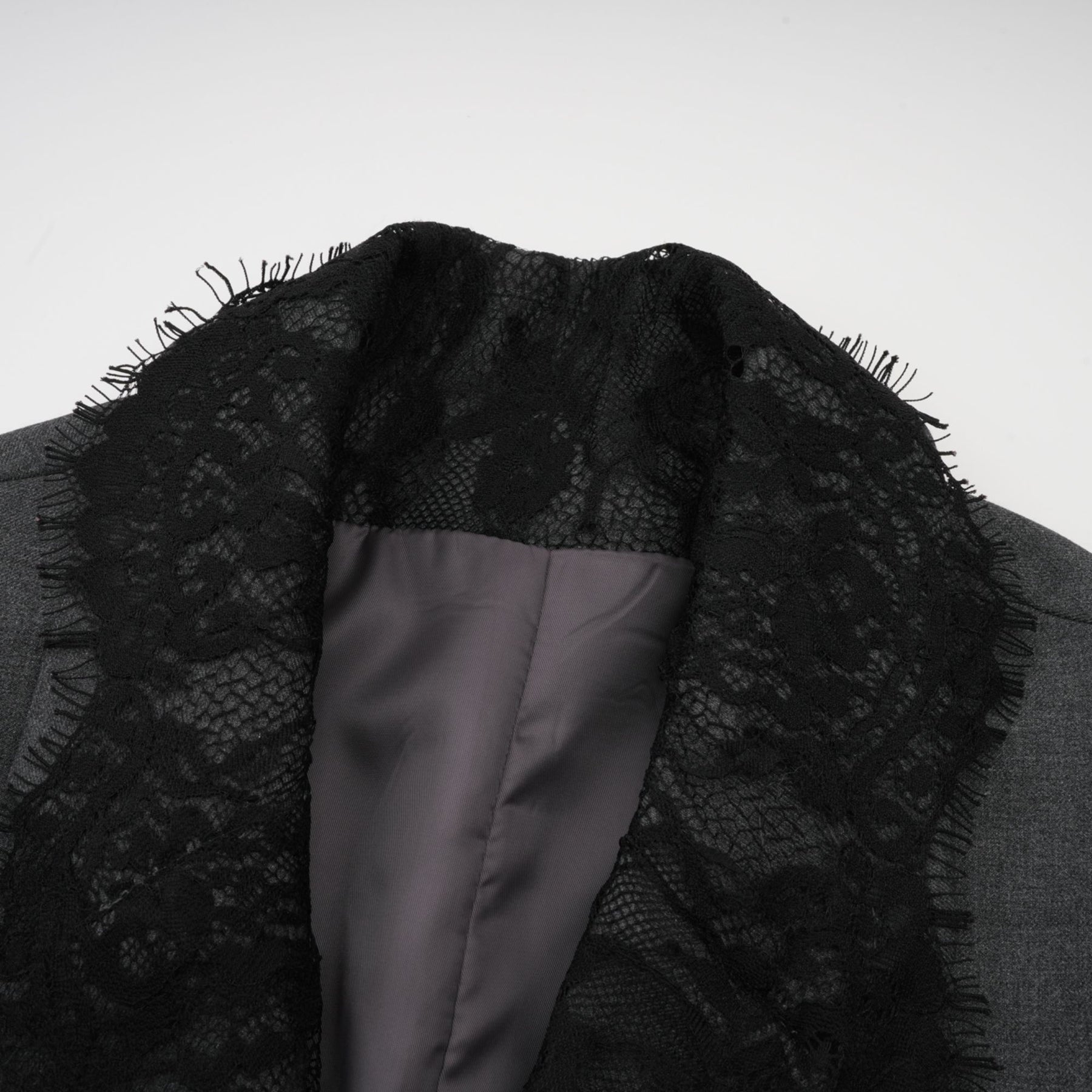 Woman wearing grey blazer with lace panel detail on sleeves and back