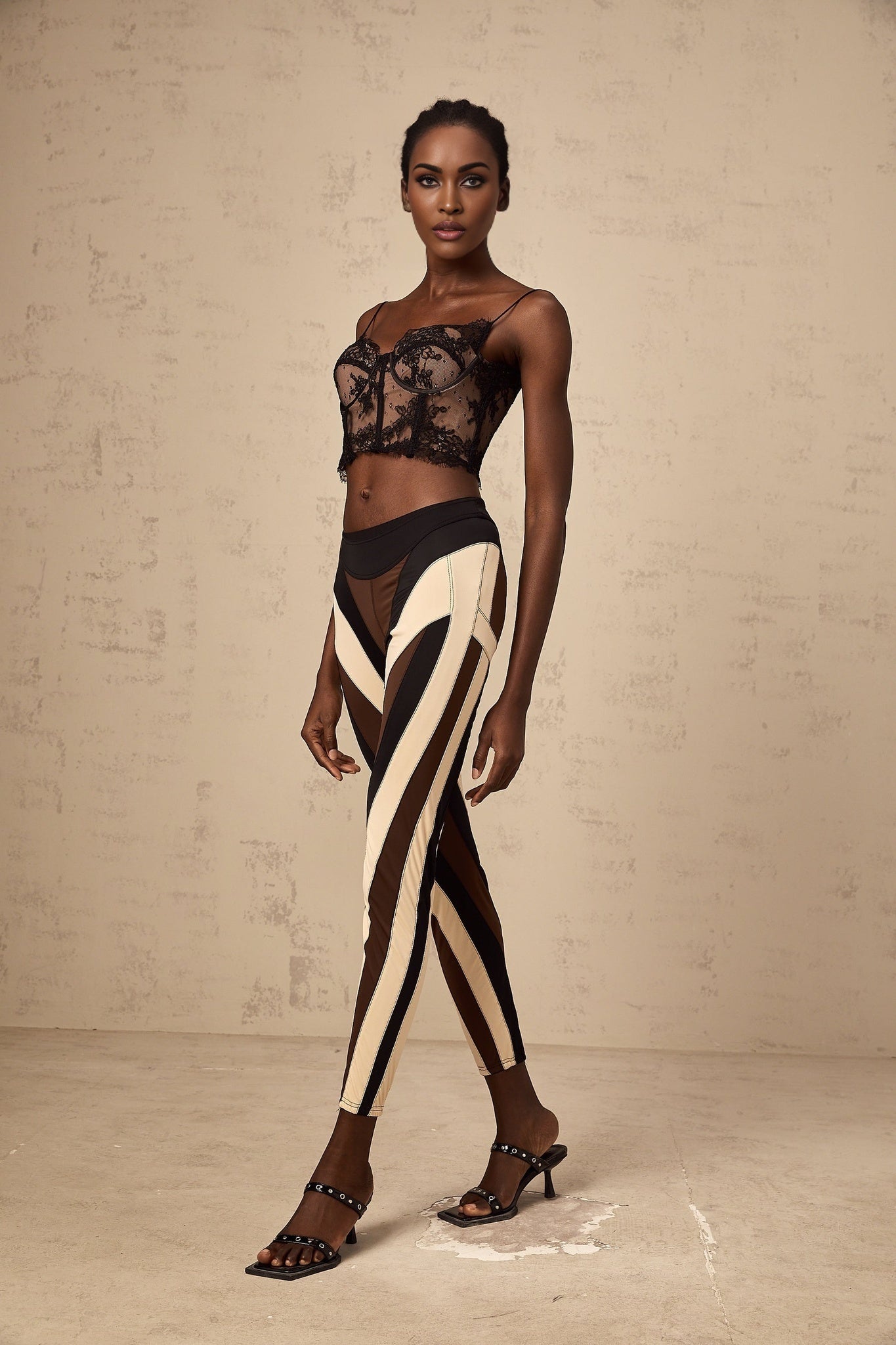 Woman wearing multicolored spiral patterned leggings with color block panels in vibrant hues standing against plain background