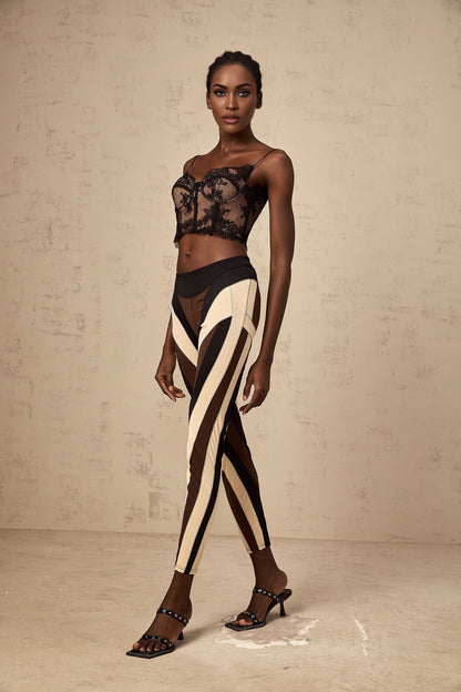 Woman wearing multicolored spiral patterned leggings with color block panels in vibrant hues standing against plain background