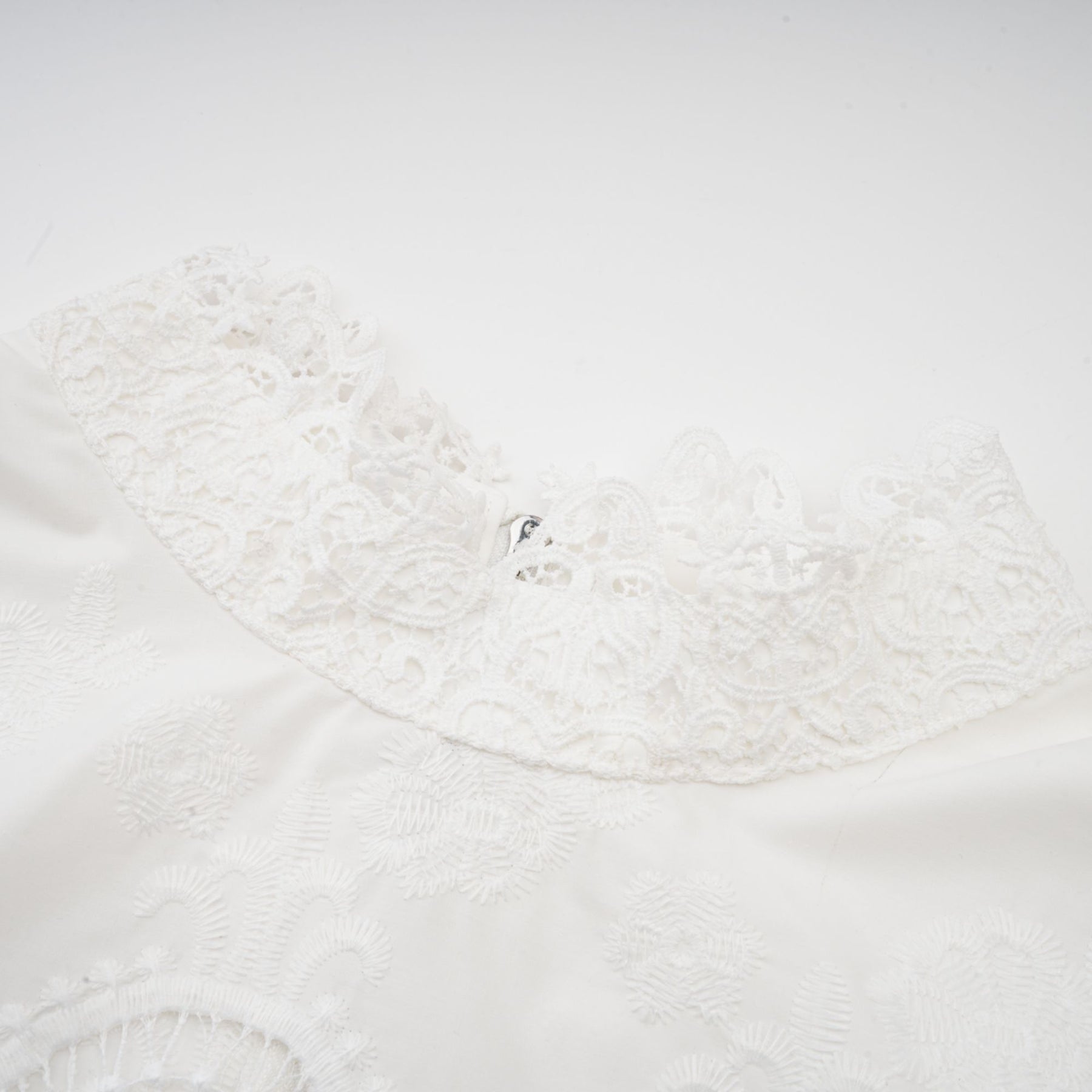 Woman wearing a matching set of white lace trimmed cropped top and trousers with cutout details