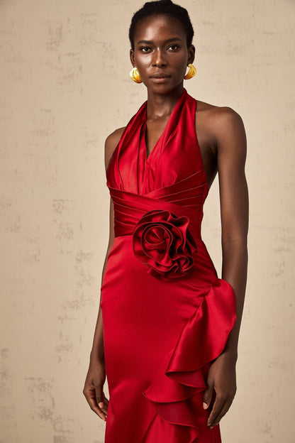 A woman wearing a vibrant red halterneck maxi dress with ruffled 3D petal details cascading down the length of the gown