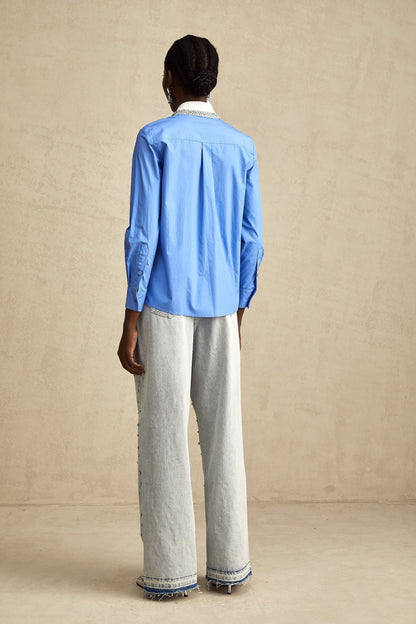 A blue shirt with a color block design featuring rhinestone embellishments named Émilie
